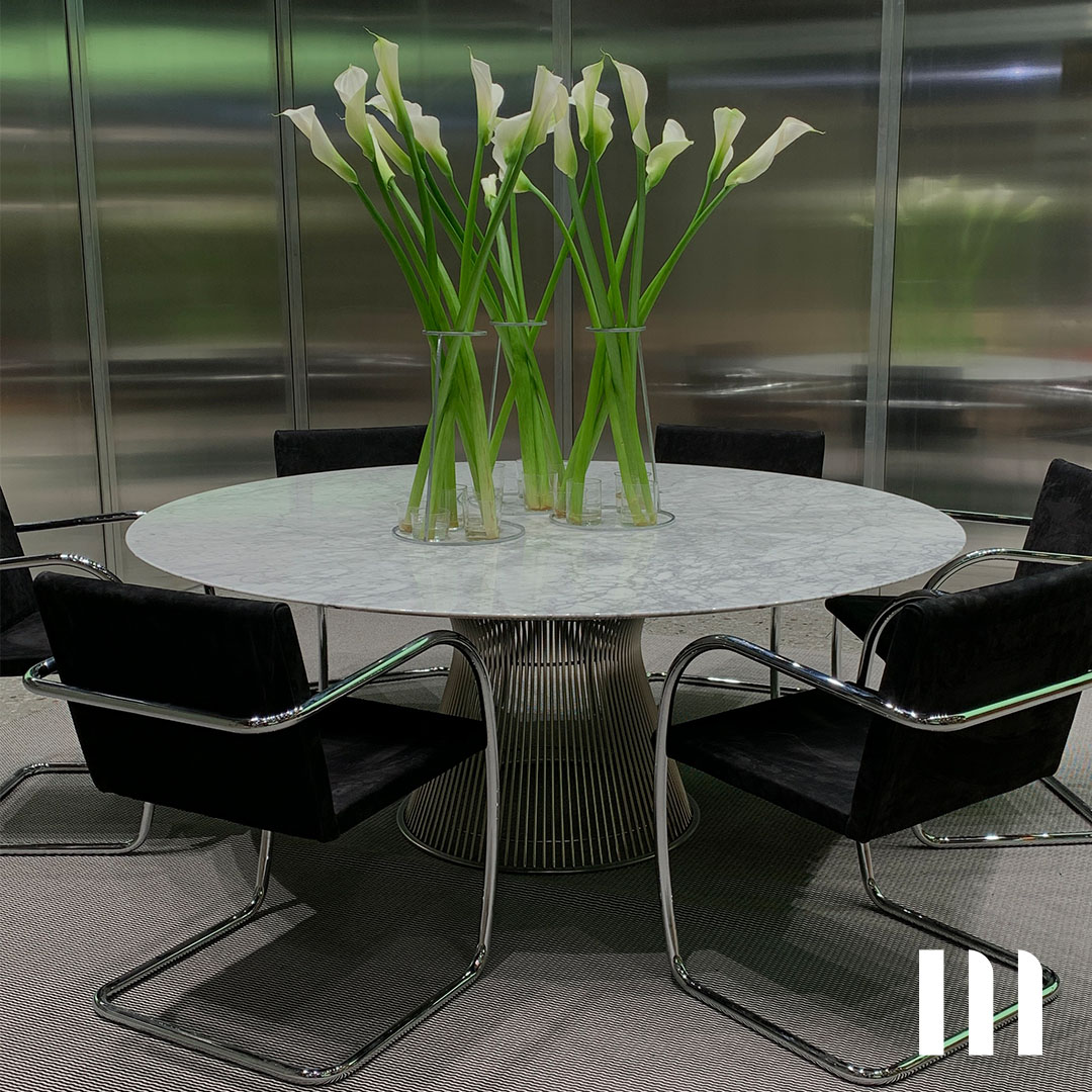 „Eleganter Esstisch mit Marmortischplatte, umgeben von schwarzen Freischwingerstühlen und minimalistischer Blumendekoration mit Calla-Lilien.