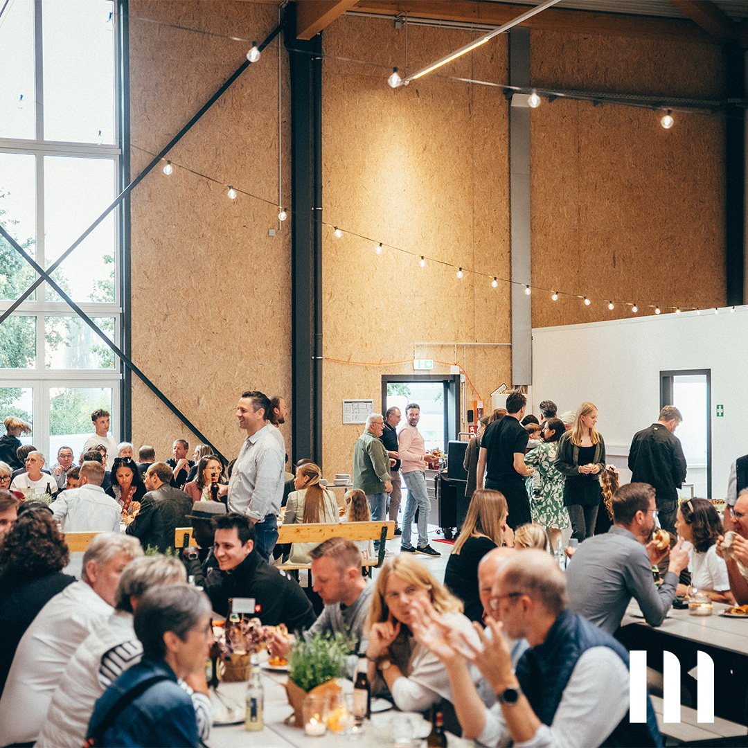 Gäste genießen das gemeinsame Essen bei der Halleneröffnung 2025 in moderner Industriehalle