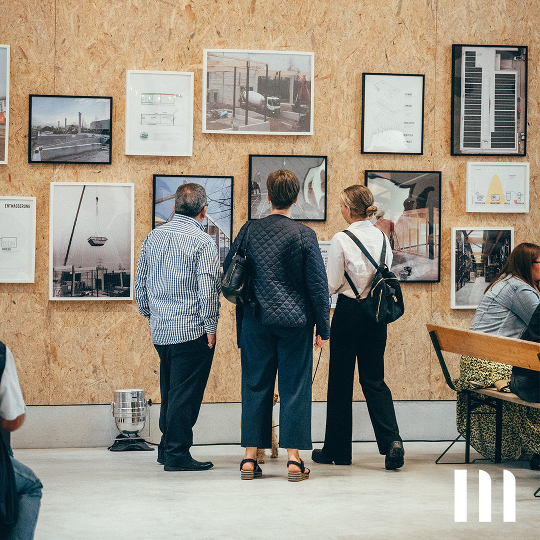Besucher betrachten Projektbilder und Baupläne auf der Historywall