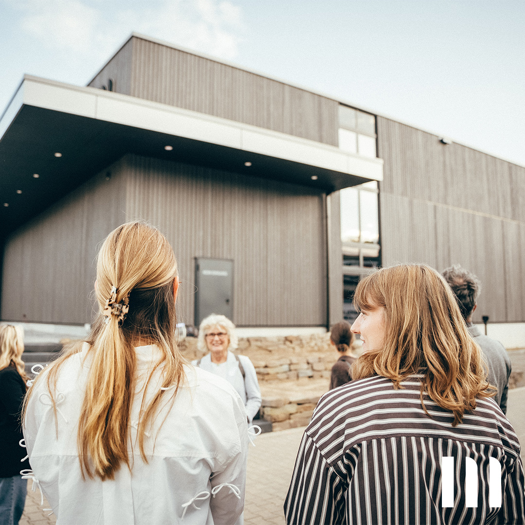 Teilnehmergruppe vor dem Neubau der Halle – moderne Architektur trifft Naturstein