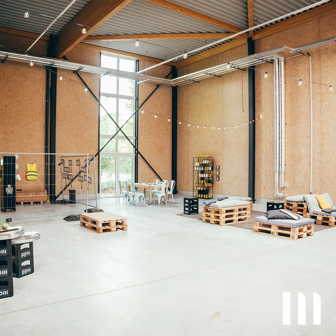 Moderner Hallenraum mit Palettenmöbeln und Lichtgirlanden – Eventfläche im neuen ppm-Gebäude